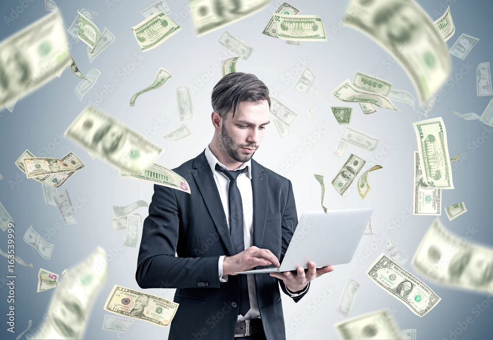 Businessman with a laptop under dollar rain