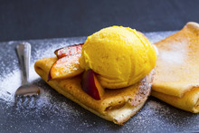 Crepes Fiiled With Jam, Peach Slices And Ice Cream Scoop On Top