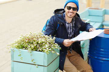 Wall Mural - Tourist with map sitting on bench in urban environment