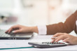 © chaiya - A business woman analyzing investment charts at his workplace and using his laptop and touch calculator.