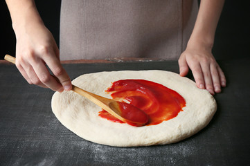 Canvas Print - Female hands making traditional pizza on black table, close up