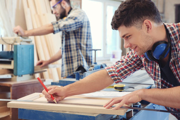 Poster - Carpenter applying marking onto wooden board in workshop