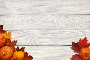 Poster - Autumn leaves and pumpkins over old wooden background