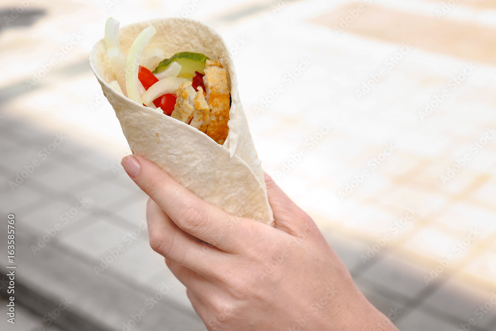 Woman holding fish taco outdoor
