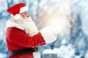 Wall Mural - Santa Claus holding magical light in hands on blurred background