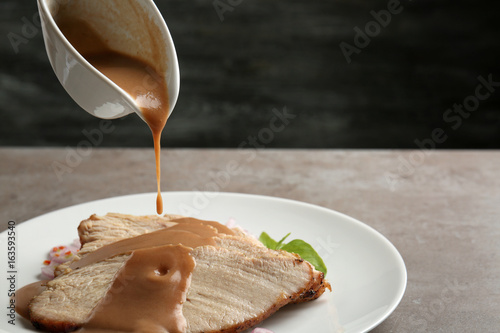 Fotomural Pouring tasty turkey gravy onto sliced meat on plate against dark background