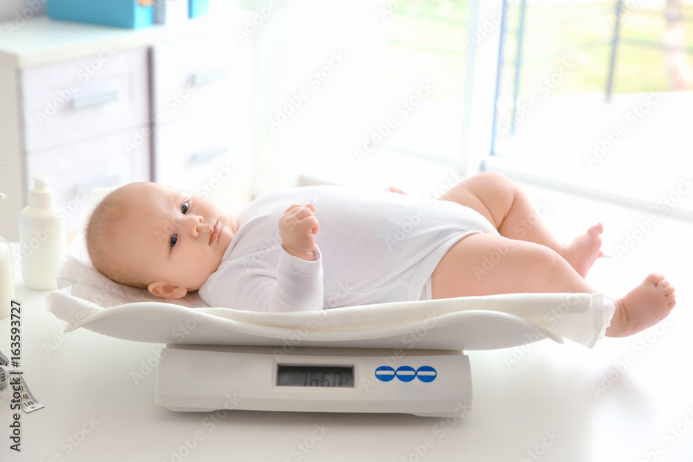 Baby lying on scales in room