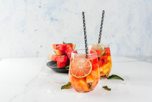 Summer Drinks And Cocktails. Lemonade, Homemade Sangria With Fresh Watermelon, Lime, Mint And Pineapple. In Two Glasses,  On A White Marble Table. Copy Space