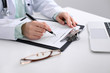 © rogerphoto - Close-up of a female doctor filling  out application form , sitting at the table in the hospital