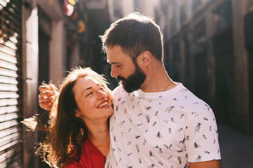 portrait of a happy couple of young lovers laughing while walking down the street on a sunny summer 
