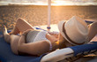 Young, pregnant woman, lying on the beach, relaxing and enjoying the sun