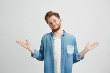 Wall Mural - Portrait of young handsome man smiling looking at camera shrugging over white background.