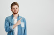 © Cookie Studio - Portrait of cheerful young handsome guy smiling looking at camera pointing finger up over white background.