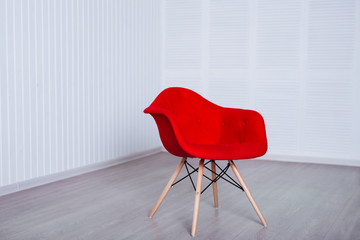 new red modern chair standing in room with white walls.
