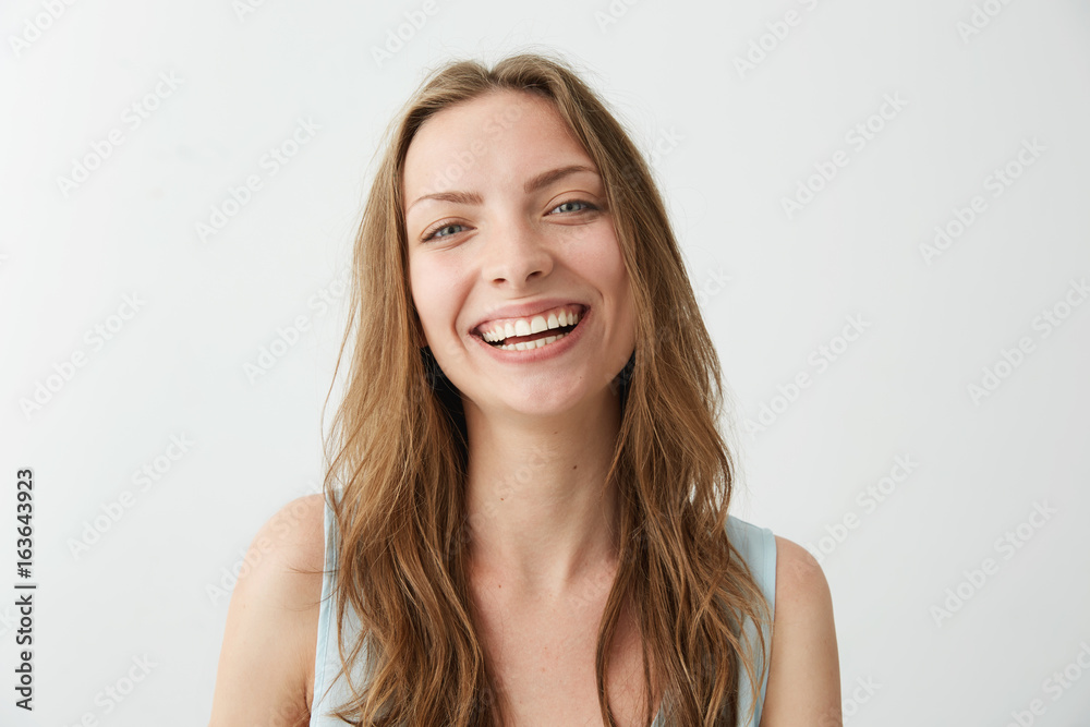 Beautiful sincere happy girl smiling laughing looking at camera over white background.