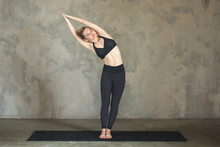 Young Woman Practicing Yoga Half Moon, Ardha Chandrasana Pose Against Texturized Wall / Urban Background