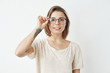 © Cookie Studio - Young pretty girl smiling looking at camera correcting glasses over white background.