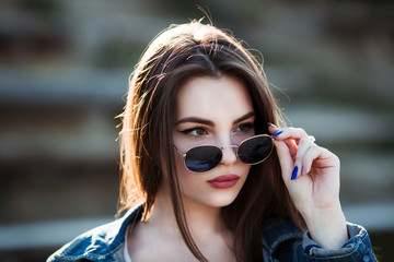 Outdoor fashion closeup portrait of young pretty woman in summer sunny day on street