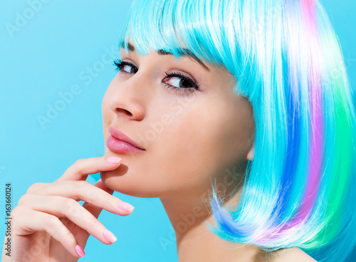 Beautiful woman in a bright blue wig on a blue background
