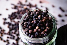 Spicy Peppercorns In A Glass Jar On A Wooden Background.