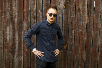 Wall Mural - Young man in sunglasses near a vintage wooden wall