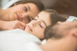 © realstock1 - The little girl sleeping near the parents on the bed