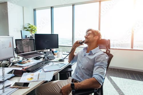Cuadros en Lienzo Business investor in a happy mood talking over phone in office.