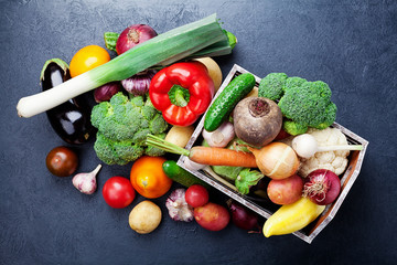 Wall Mural - Wooden box with autumn harvest farm vegetables and root crops on black kitchen table top view. Healthy and organic food.