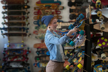 Woman Working In Skateboard Shop, Organising Skateboard Display