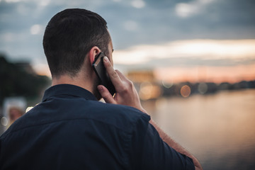 Businessman talking on mobile phone looking at evening city