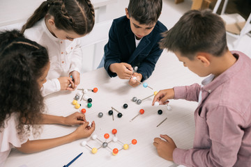 Wall Mural - Concentrated multiethnic schoolkids studying with molecular model at chemistry lesson