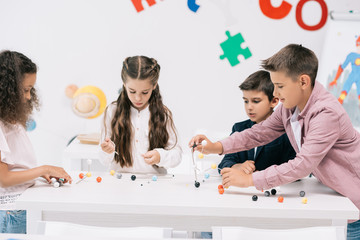 Wall Mural - Multiethnic group of schoolchildren studying with molecular model at chemistry lesson