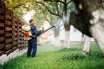 Farmer worker spraying pesticide treatment on fruit garden