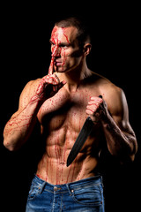 scary fitness muscular male model covered in blood with knife