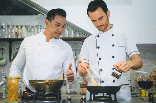 Zdjęcie XXL Dwóch młodych szefów kuchni przygotowuje i gotuje jedzenie w kuchni restauracji