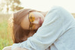 © annaazary - Beautiful young girl in a T-shirt is sitting in the grass at sunset wearing yellow glasses, good mood, smiling