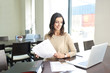 © gzorgz - Doing some paperwork at office. Shot of a young professional woman sitting at desk in front of laptop and working on business conctract.