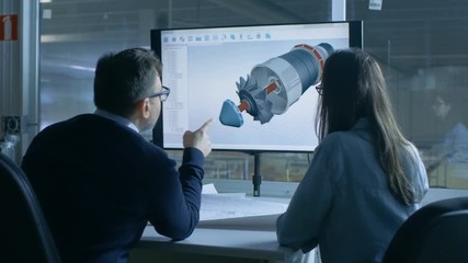 Male and Female Engineers Work With Blueprints while Presentation Display Shows 3D Model of a Turbine/Engine Part. In Background Functional Plant is Seen. Shot on RED EPIC-W 8K Helium Cinema Camera.