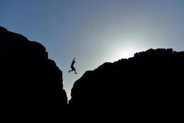 man who jumped on the rocks in silhouette