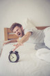 © NT_studio - man sleepy nationality american reaching for the alarm clock sleeping on bedroom.