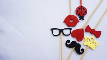 Top Or Flat Lay View Of Photo Booth Props A Black Mustache A Black Glases, A Red Bow Tie, A Ladybird, A Red Heart Shape, A Red Lips And A Yellow Crown On A White Isolated Background Flat Lay. Birthday