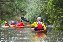 Group Of People (friends) Kayaking In Wild River Among Thickets Of Plants On Biosphere Reserve In Spring