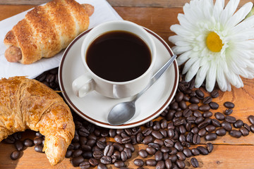 Breakfast with coffee, croissant and sausage dough on wooden table