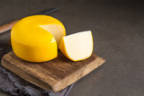 Fototapeta  - Round gouda cheese. Dark background.
