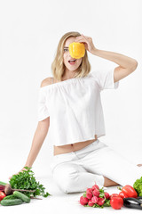 Sticker - Beautiful blond woman in white clothes and lots of fresh vegetables on white background. Girl holds bell pepper