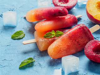 Close up view of plum and peach popsicle on blue background