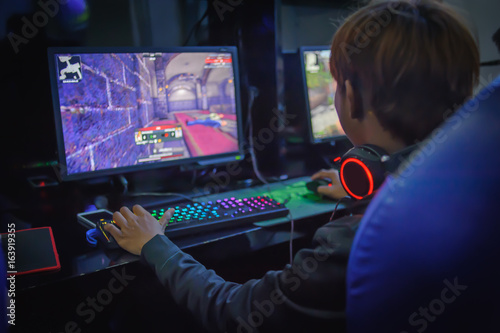 Plakat młody człowiek, grając w gry komputerowe w kafejce internetowej