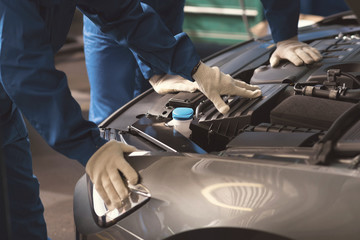 Two professionals examining cars engine