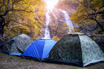 Camping tent and autumn leaves with waterfall in deep forest  Khlong Lan Waterfall in Thailand.