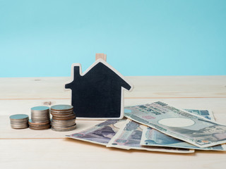 coin stack with house model, savings plans for housing blue background, financial concept. House and coins on table.Concept for property ladder, mortgage and real estate investment.